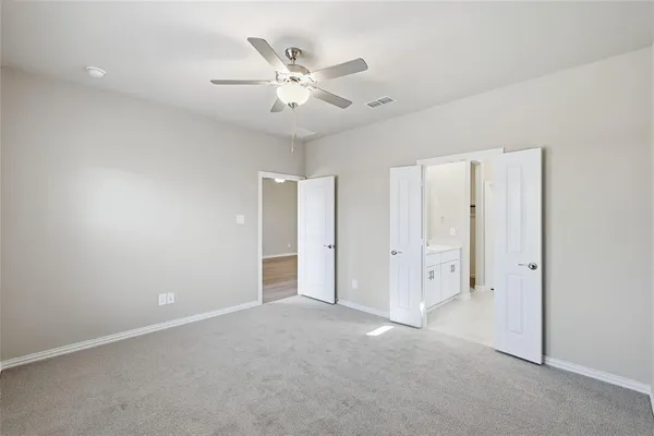 an empty room with chandelier fan and closet