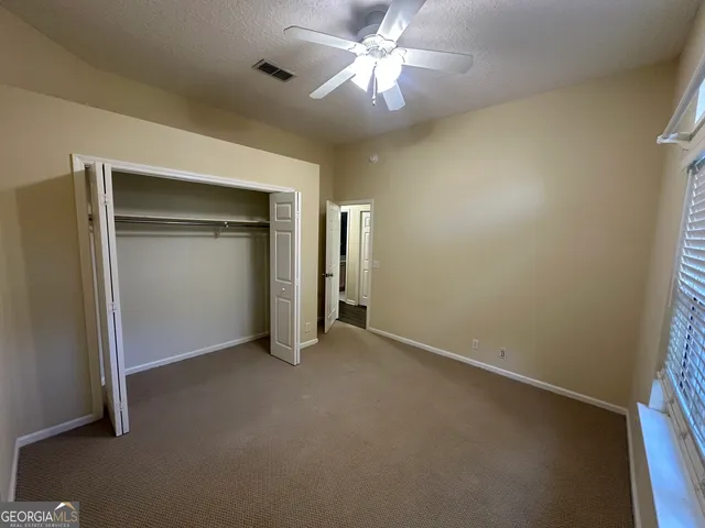 an empty room with closet and a ceiling fan