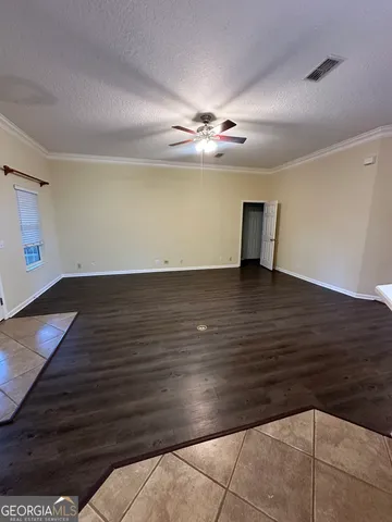 a view of an empty room with wooden floor and a ceiling fan