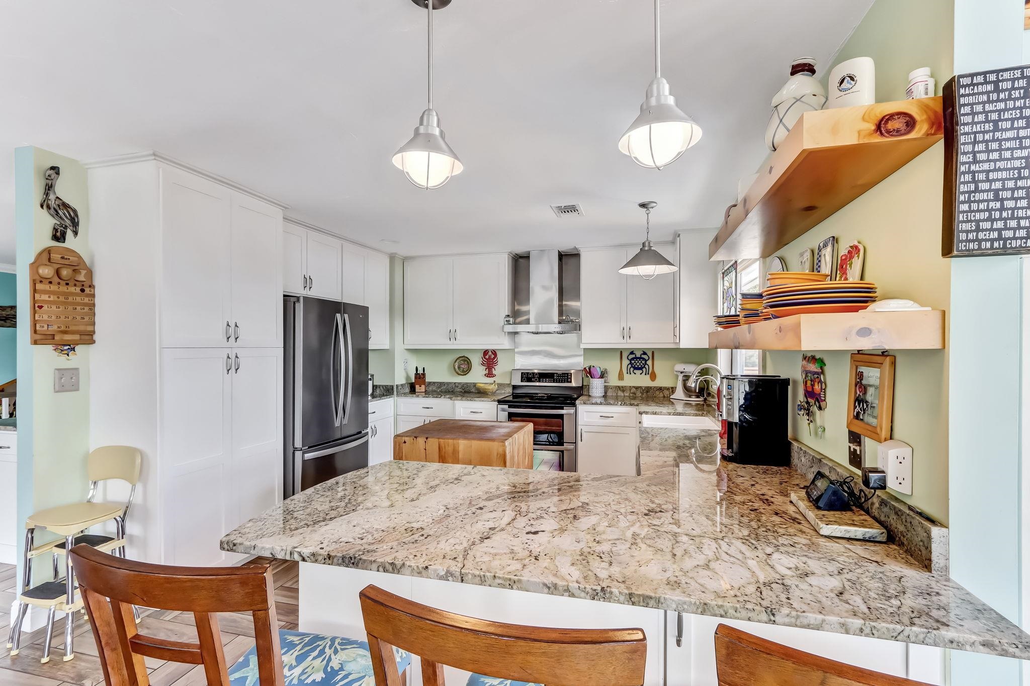 247 Treasure Beach Road St. Augustine, FL 32080 - Photo 5 of 28 a kitchen with stainless steel appliances kitchen island granite countertop a refrigerator a stove a sink dishwasher and a dining table with wooden floor