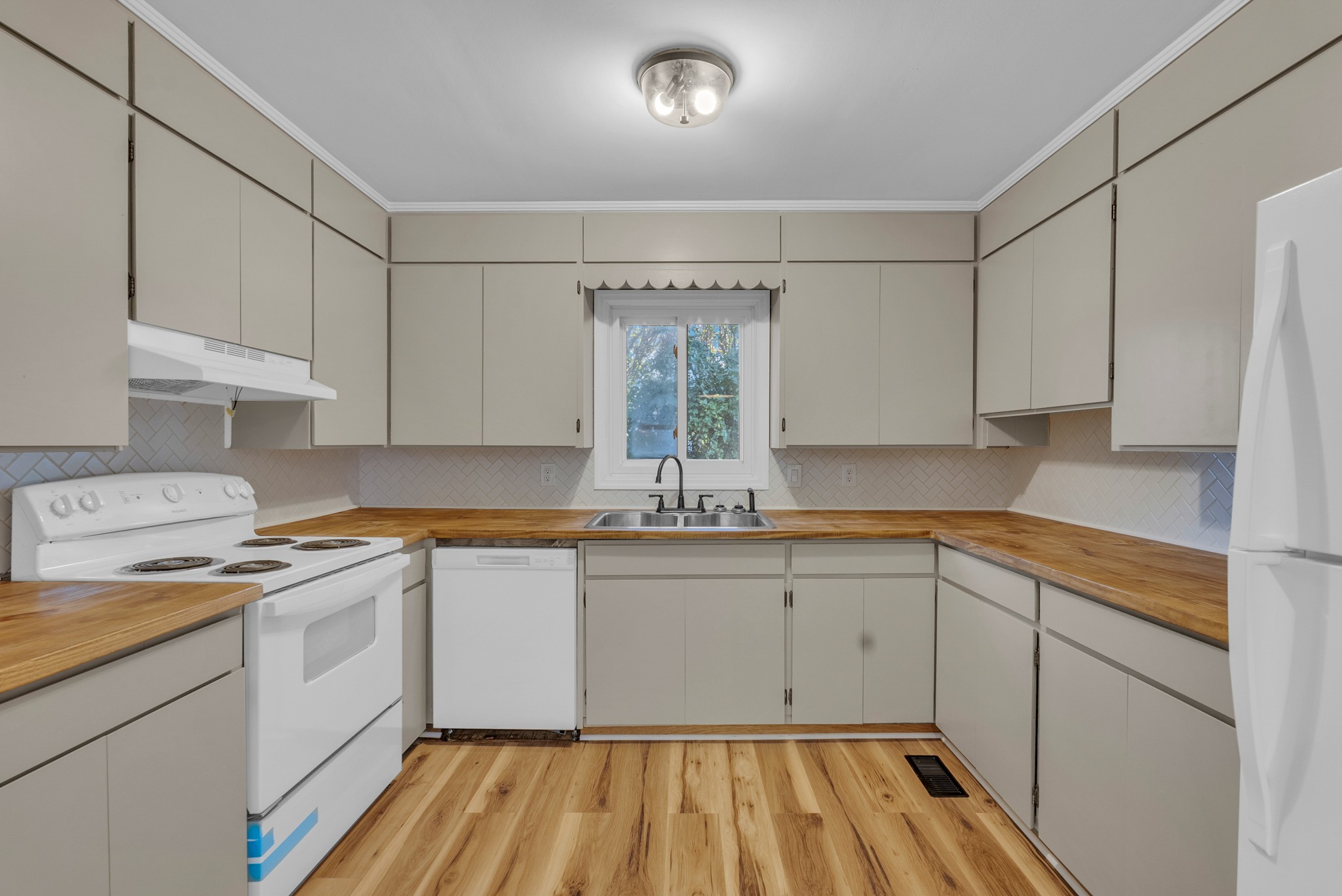107 Oak Street Sparta, TN 38583 - Photo 6 of 26 a kitchen with a sink dishwasher a stove and white cabinets with wooden floor