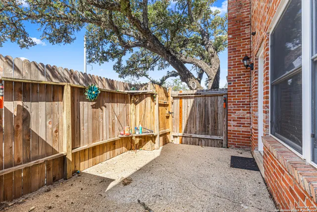 a view of backyard with wooden fence and large trees