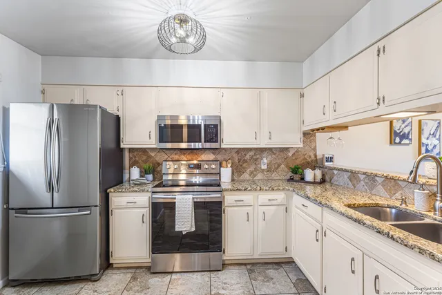a kitchen with stainless steel appliances granite countertop a sink a stove a refrigerator and cabinets
