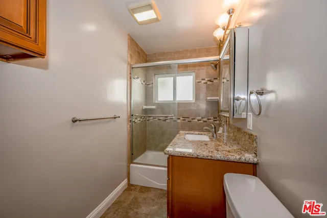 a bathroom with a granite countertop sink a toilet and shower