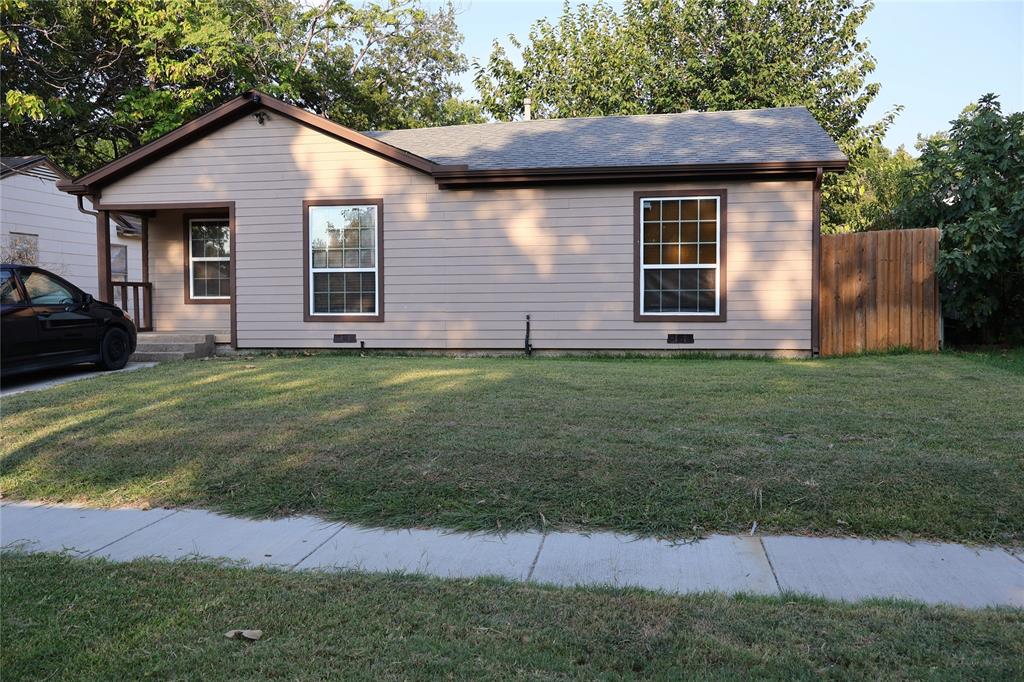 a view of a yard in front of a house with plants and large tree