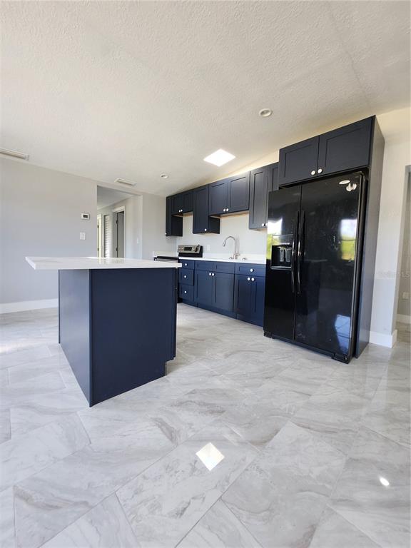 1302 West Shell Point Road Ruskin, FL 33570 - Photo 2 of 10 a kitchen with stainless steel appliances kitchen island granite countertop a refrigerator and a sink