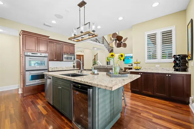 a kitchen with stainless steel appliances granite countertop a sink a stove and a wooden floors