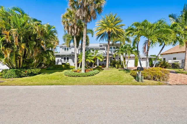 a view of a house with a yard and palm trees