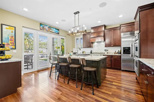 a kitchen with stainless steel appliances granite countertop a table chairs and a refrigerator