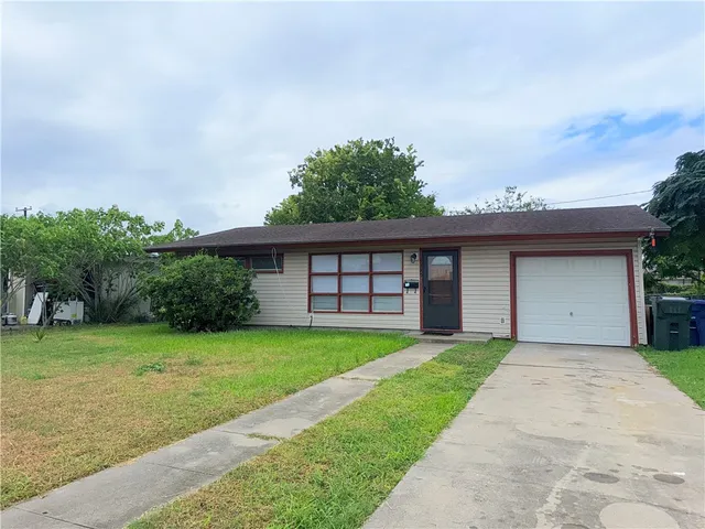 a view of a yard in front of a house with a large tree
