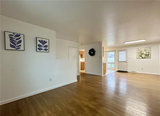 a view of an empty room with window and wooden floor