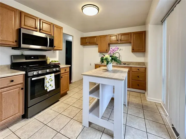a kitchen with kitchen island granite countertop a stove top oven microwave and cabinets
