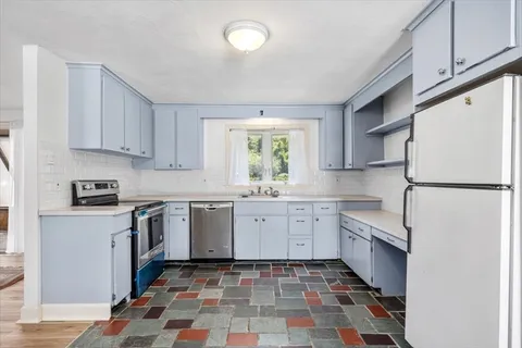 a kitchen with granite countertop a sink cabinets and stainless steel appliances