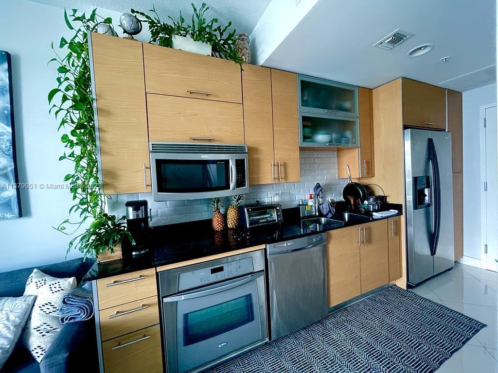 60 Southwest 13th Street, Unit 2413 Miami, FL 33130 - Photo 10 of 27 a kitchen with a potted plant on the counter and a wooden floor