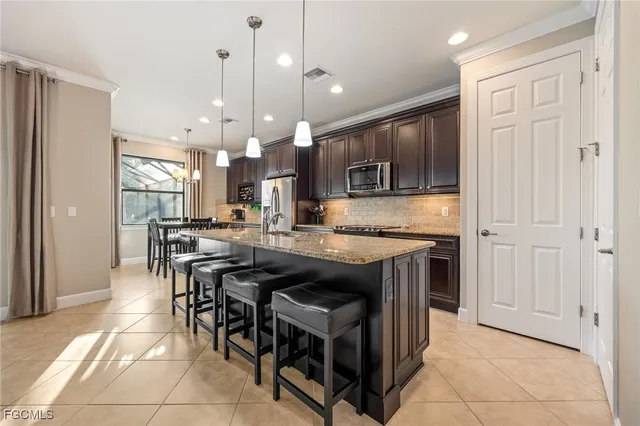 a kitchen with stainless steel appliances granite countertop a refrigerator a sink a stove and a center island
