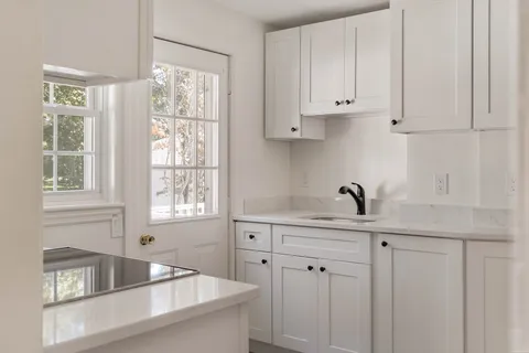 a kitchen with stainless steel appliances white cabinets a window and a sink