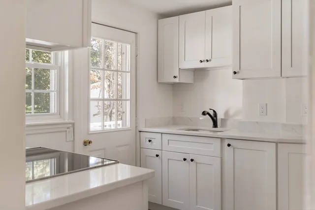 a kitchen with stainless steel appliances white cabinets a window and a sink
