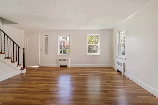 a view of an empty room with window and wooden floor
