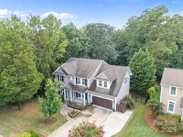an aerial view of a house with garden space and trees in the background