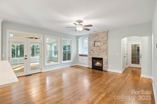 a view of a livingroom with a fireplace a chandelier and windows