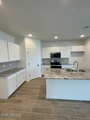 a large kitchen with granite countertop a stove a sink a granite counter space and cabinets