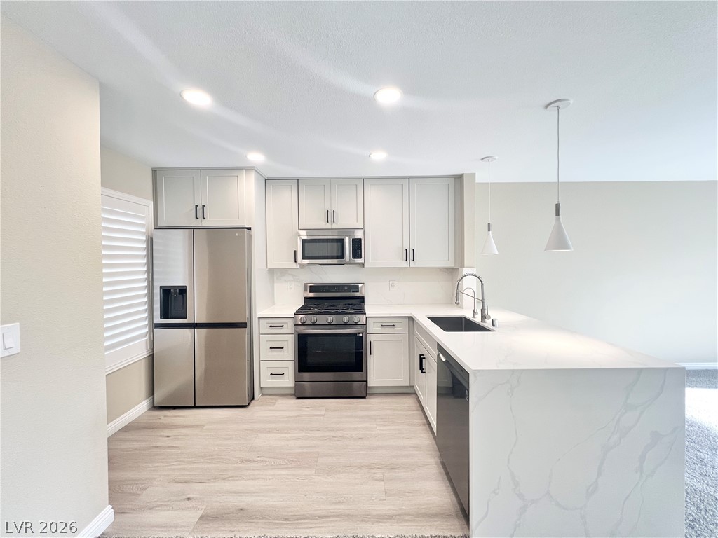 Kitchen w/ light grey cabinets, quartz countertops with waterfall, SS appliances, undermounted single basin sink & single handle spring neck faucet & pendant lighting