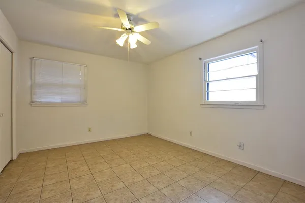 an empty room with a chandelier fan and windows