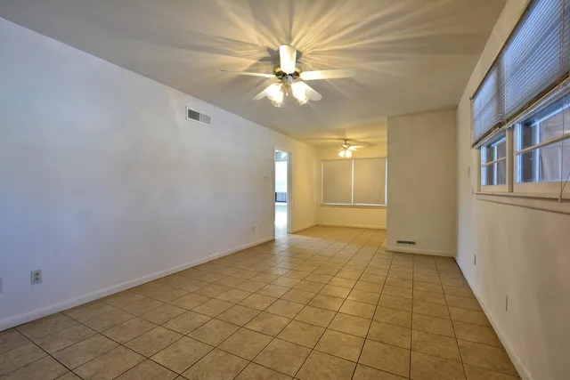 a view of an empty room and chandelier fan