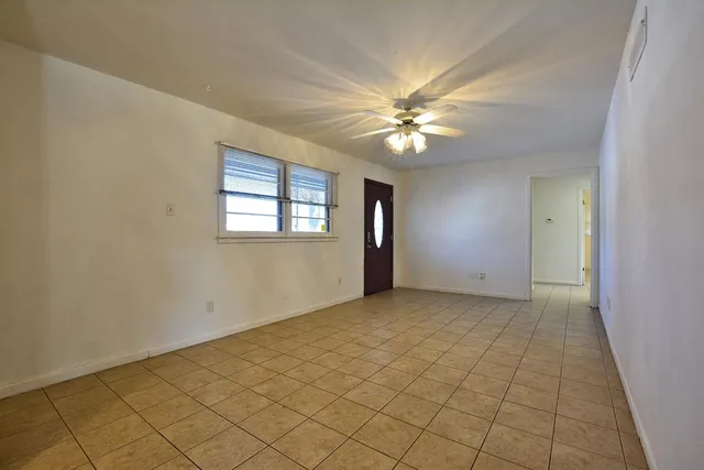 an empty room with windows and fan