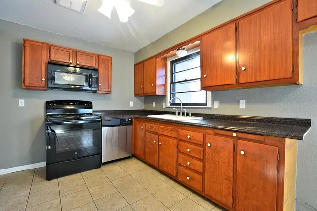 a kitchen with stainless steel appliances granite countertop a stove sink microwave and window