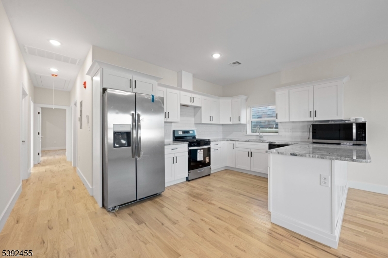 56 Second Street Elizabeth Port, NJ 07206 - Photo 11 of 28 a kitchen with stainless steel appliances kitchen island granite countertop a refrigerator a stove top oven a sink and dishwasher with wooden floor