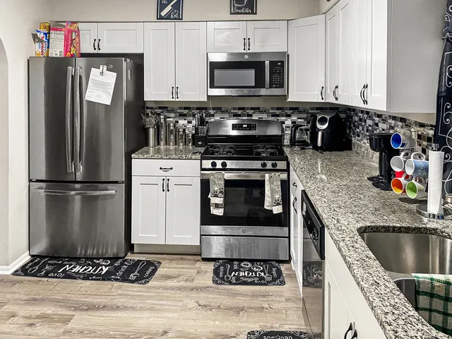 a kitchen with stainless steel appliances granite countertop a refrigerator stove and sink