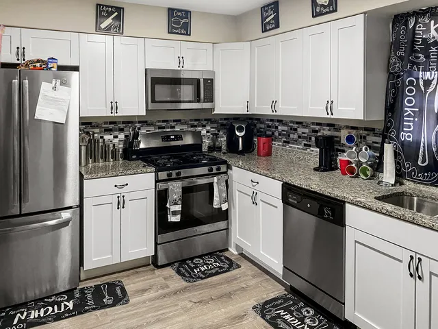 a kitchen with granite countertop a refrigerator stove and microwave