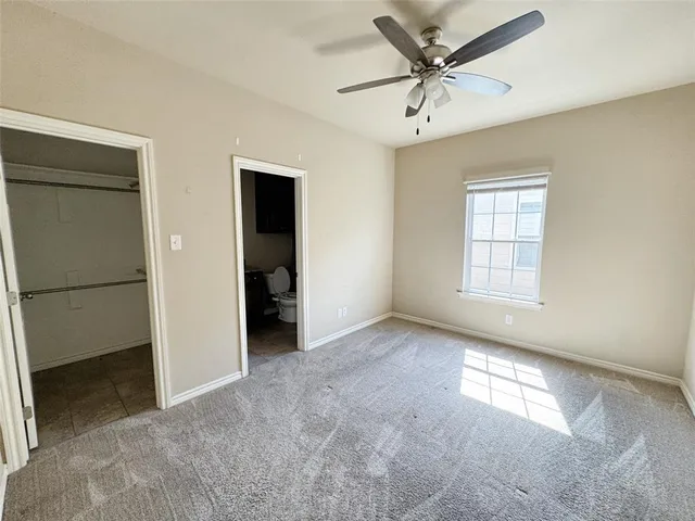 an empty room with closet and a ceiling fan