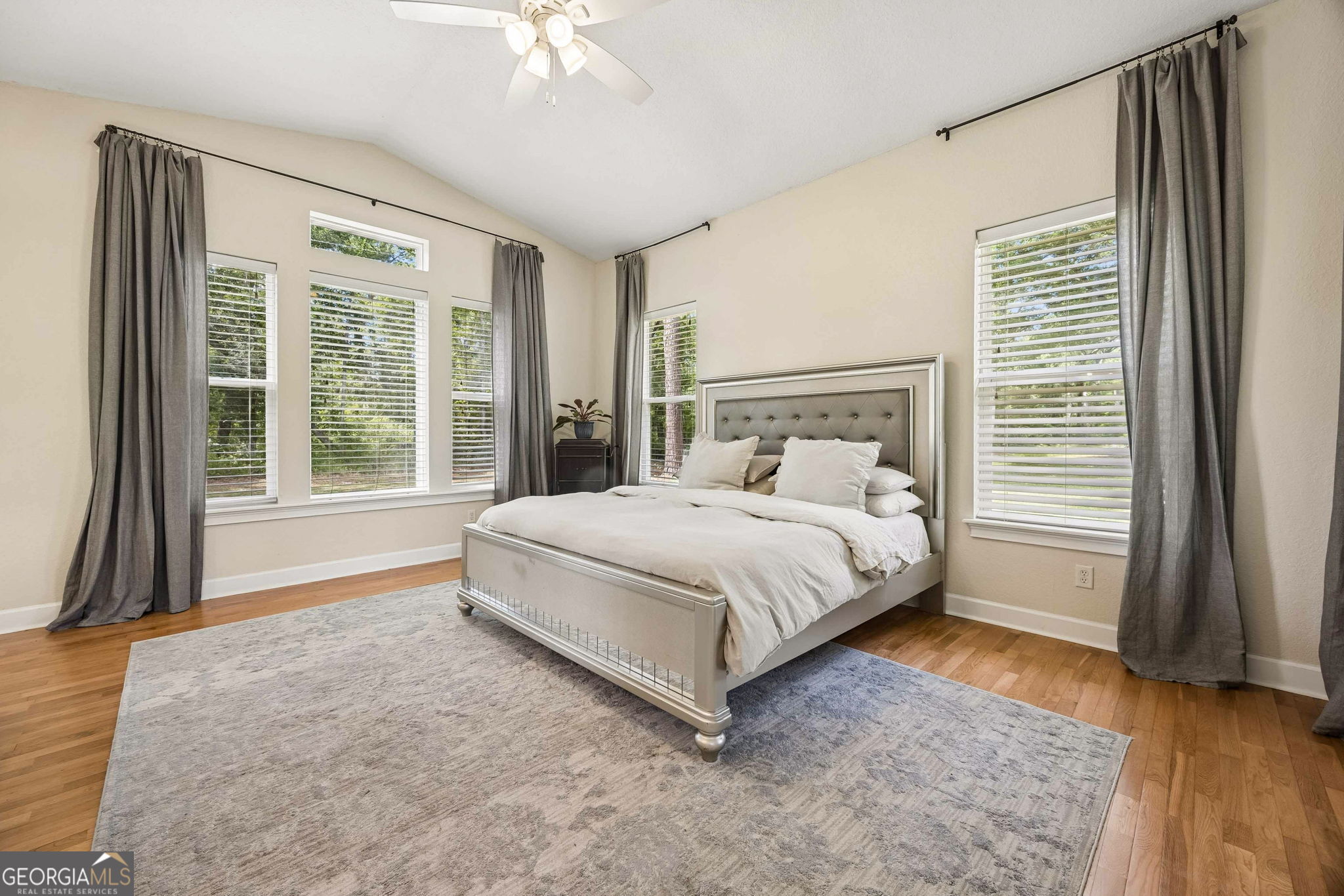 706 Hopewell Point Road White Oak, GA 31568 - Photo 29 of 84 Spacious and serene, the primary suite features hardwood flooring, vaulted ceilings, abundant natural light, and peaceful views of the surrounding property.
