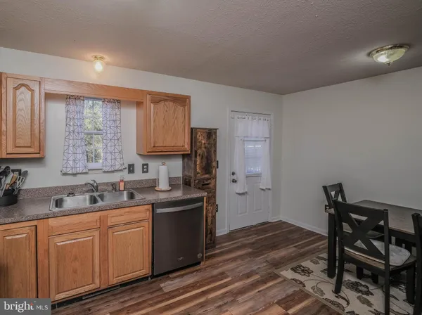 a kitchen with stainless steel appliances granite countertop a sink dishwasher a refrigerator and cabinets with wooden floor