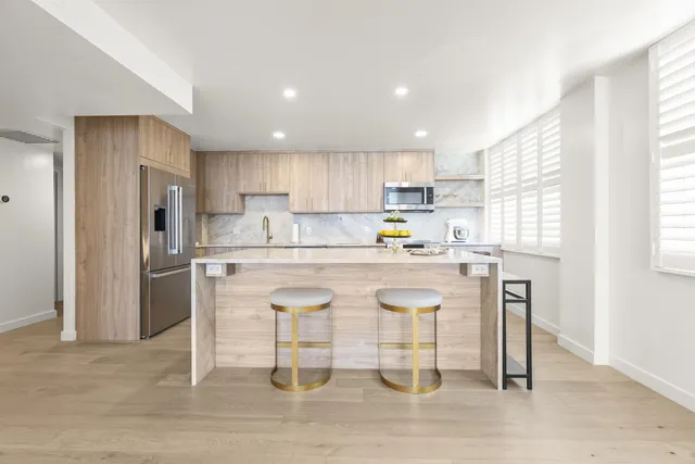 a kitchen with stainless steel appliances granite countertop a refrigerator a stove a sink and white cabinets with wooden floor