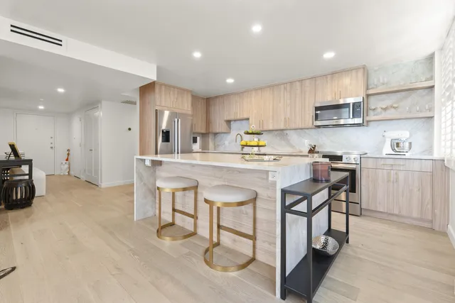 a kitchen with stainless steel appliances granite countertop a table chairs sink refrigerator and cabinets