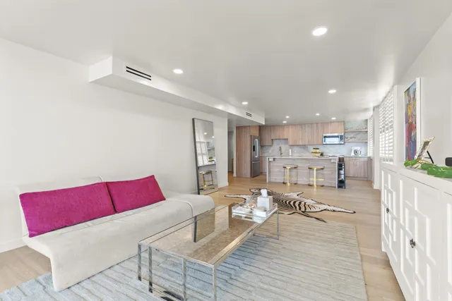 a living room with furniture kitchen view and a wooden floor