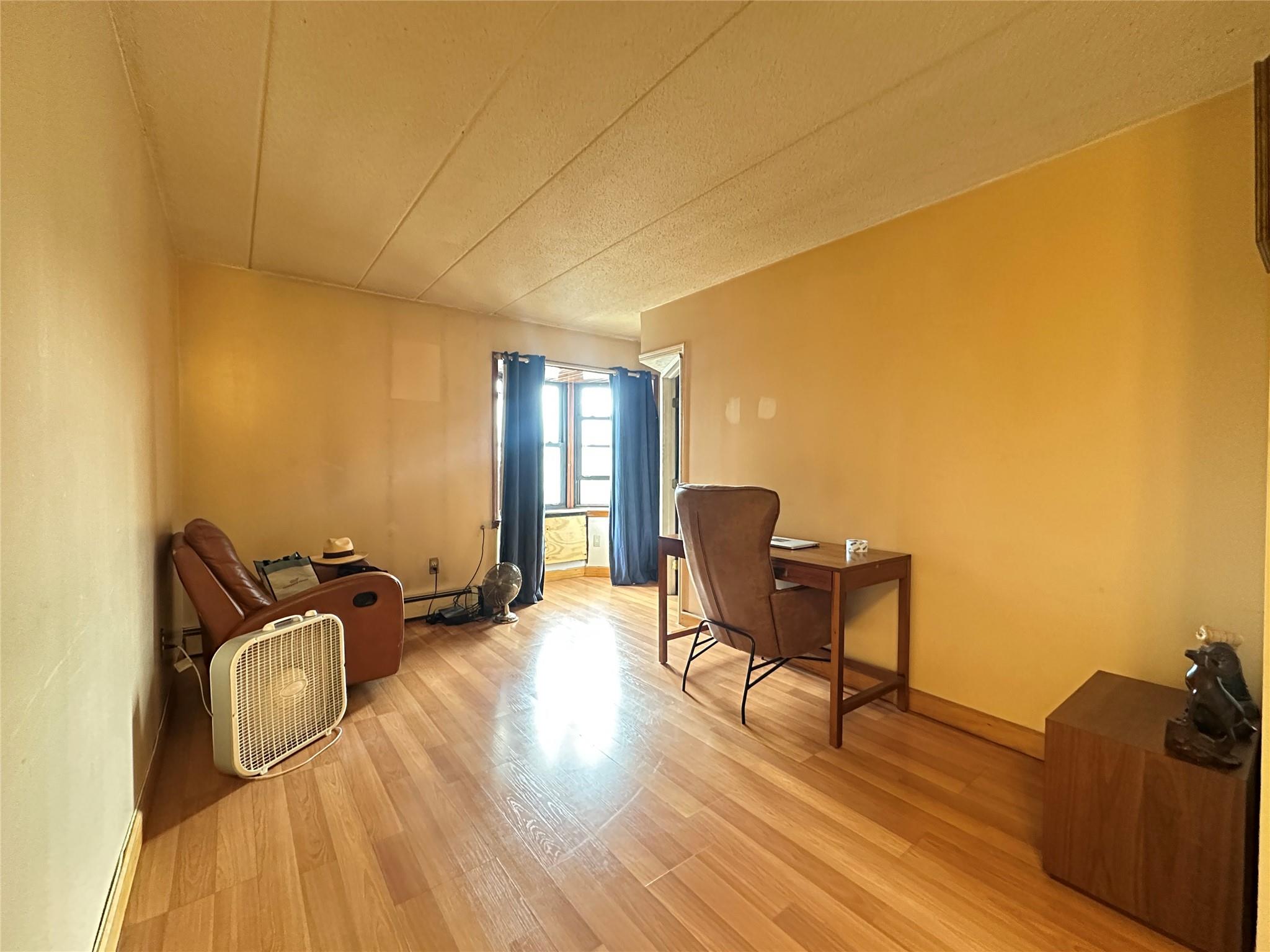 130-14 60th Avenue, Unit 2E Queens, NY 11355 - Photo 3 of 8 Living area with light wood-style floors and baseboard heating