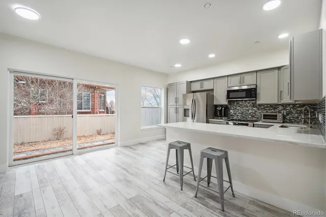 a large white kitchen with wooden floor and stainless steel appliances
