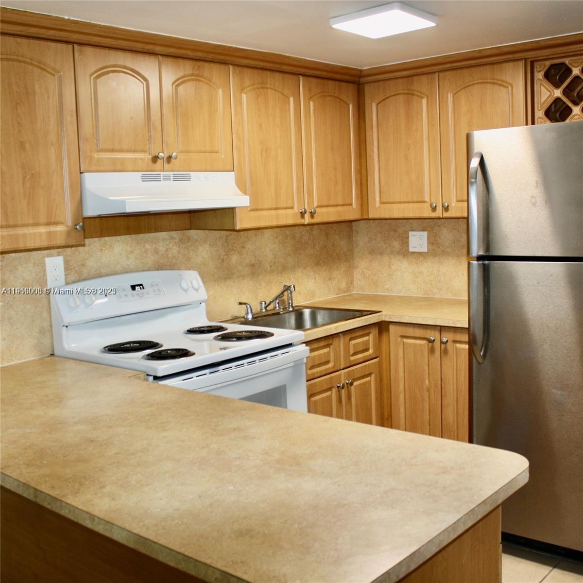 2079 West 54th Terrace, Unit 29 Hialeah, FL 33016 - Photo 16 of 43 a kitchen with stainless steel appliances a refrigerator a sink and white cabinets