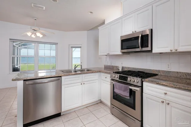 a kitchen with granite countertop white cabinets and stainless steel appliances