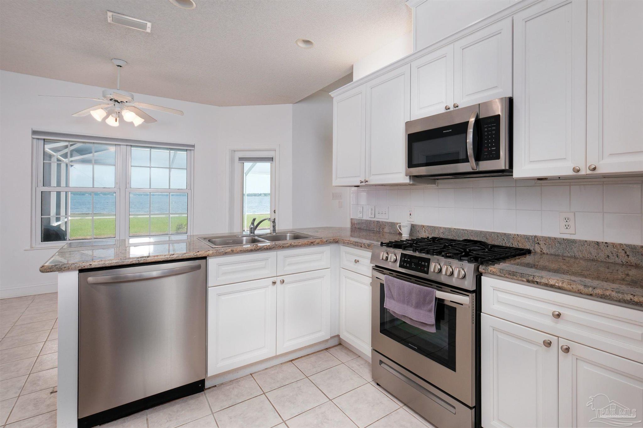 5450 North Shore Road Pensacola, FL 32507 - Photo 24 of 62 a kitchen with stainless steel appliances granite countertop grey cabinets a stove a sink and a microwave