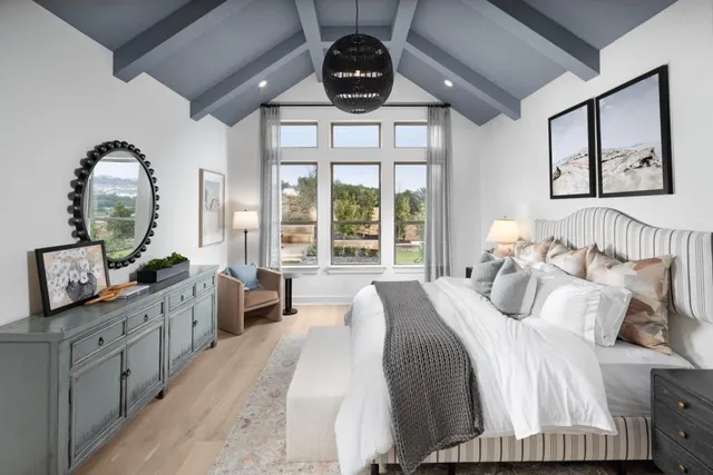 a bedroom with a bed a chandelier and large windows