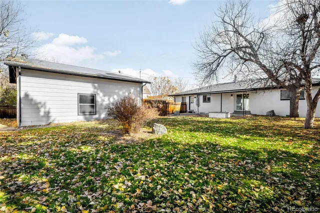 a backyard of a house with table and chairs under an umbrella