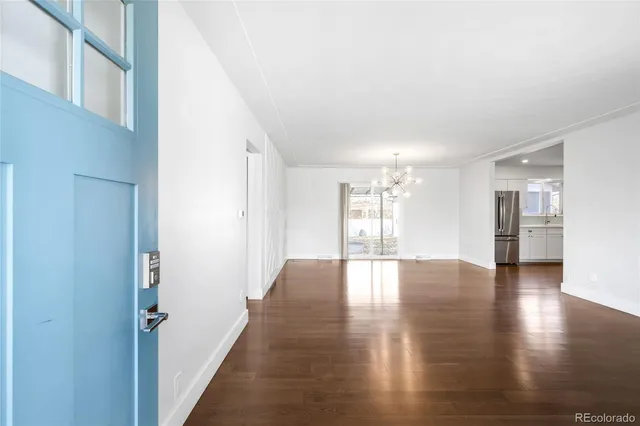 an empty room with wooden floor and kitchen view