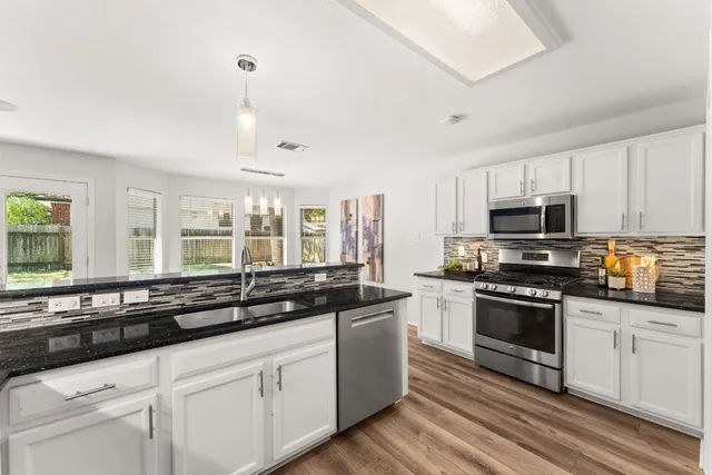 a kitchen with granite countertop white cabinets and stainless steel appliances