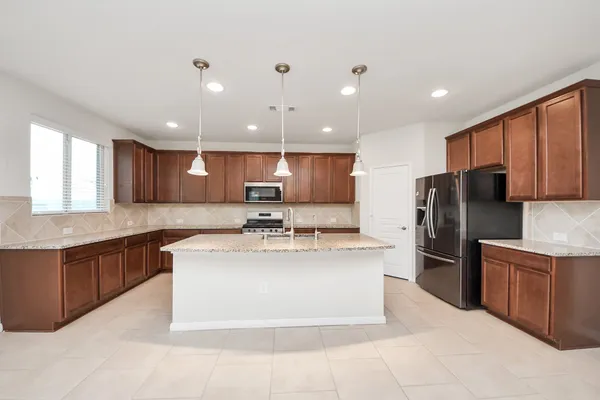 a large kitchen with stainless steel appliances kitchen island granite countertop a large counter top and a stove top oven