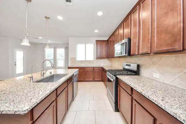 a kitchen with granite countertop cabinets a sink dishwasher a dining table and chairs with wooden floor